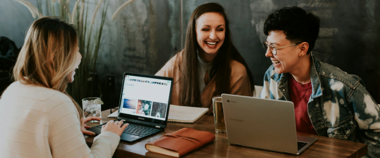 A group of women at a table working on their laptops