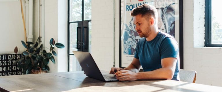 A man looking focused working on his laptop